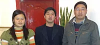 Three asian people standing in front of a red door.
